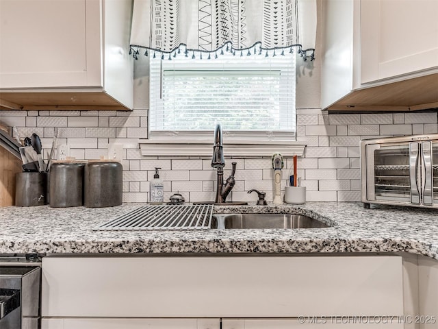 310 W Lee Ave, Sapulpa, OK 74066 - kitchen with white cabinets, tasteful backsplash, and light stone countertops