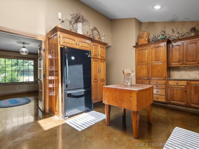 6429 Clear Creek Loop, Bartlesville, OK 74006 - kitchen with freestanding refrigerator, brown cabinets, tasteful backsplash, and a textured ceiling