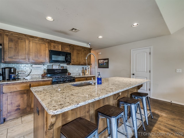 3409 E Quebec St, Broken Arrow, OK 74014 - kitchen with black appliances, decorative backsplash, light stone counters, a kitchen bar, and an island with sink