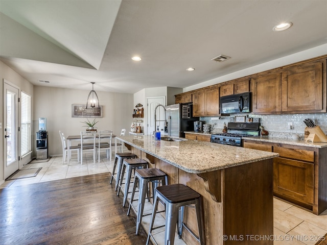 3409 E Quebec St, Broken Arrow, OK 74014 - kitchen with gas stove, black microwave, stainless steel fridge, decorative backsplash, and a kitchen breakfast bar