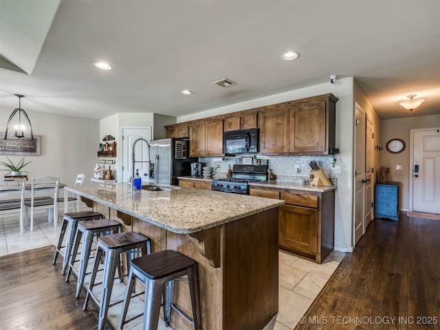 3409 E Quebec St, Broken Arrow, OK 74014 - kitchen featuring range with gas cooktop, black microwave, a breakfast bar, decorative backsplash, and stainless steel refrigerator with ice dispenser
