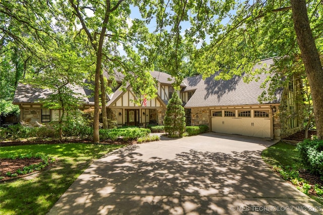 6530 E 106th St, Tulsa, OK 74133 - tudor house with stone siding, concrete driveway, a garage, and roof with shingles