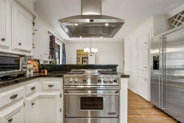 6530 E 106th St, Tulsa, OK 74133 - kitchen with high quality appliances, wall chimney range hood, a chandelier, white cabinetry, and a peninsula