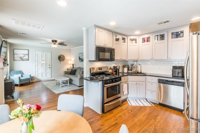 2648 E 2nd St, Tulsa, OK 74104 - kitchen with appliances with stainless steel finishes, open floor plan, light wood finished floors, dark countertops, and recessed lighting