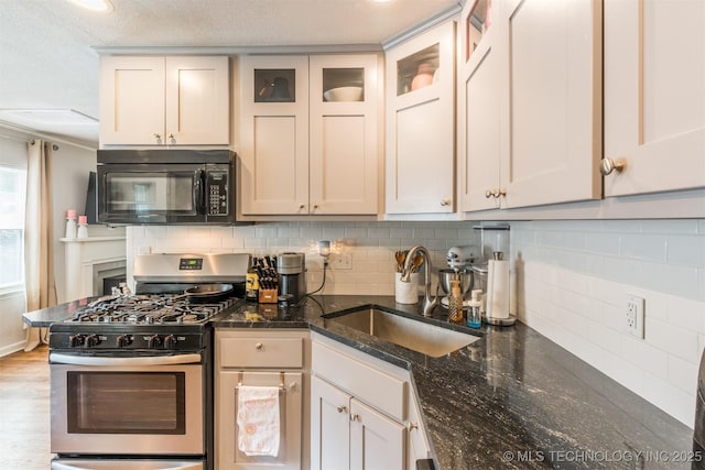 2648 E 2nd St, Tulsa, OK 74104 - kitchen featuring black microwave, stainless steel gas range, tasteful backsplash, dark stone countertops, and wood finished floors