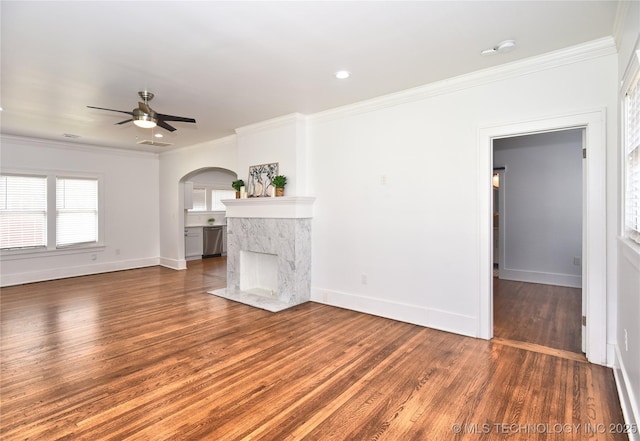 2020 E 14th St, Tulsa, OK 74104 - unfurnished living room featuring arched walkways, a ceiling fan, ornamental molding, wood finished floors, and a fireplace