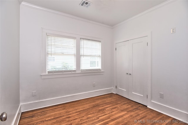 2020 E 14th St, Tulsa, OK 74104 - unfurnished bedroom featuring crown molding, dark wood-style flooring, and a closet