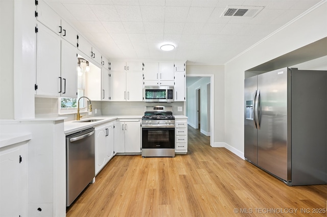 202 W Burnham Ave, Sapulpa, OK 74066 - kitchen with stainless steel appliances, light countertops, light wood-style flooring, white cabinets, and ornamental molding