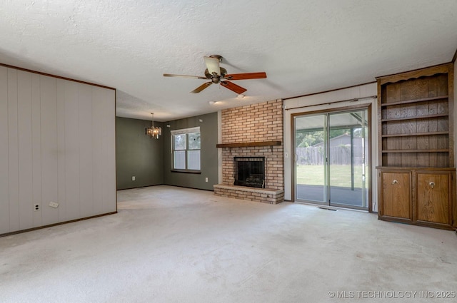 606 N Gum St, Jenks, OK 74037 - unfurnished living room featuring a chandelier, ceiling fan, a brick fireplace, carpet flooring, and a textured ceiling