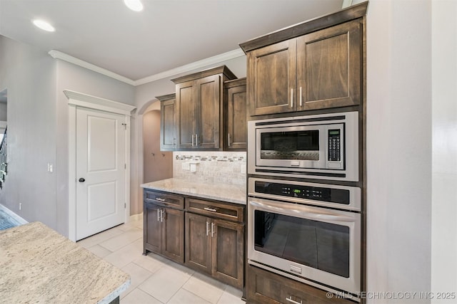 6107 E 127th St N, Collinsville, OK 74021 - kitchen with appliances with stainless steel finishes, arched walkways, crown molding, tasteful backsplash, and light tile patterned floors