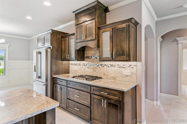 6107 E 127th St N, Collinsville, OK 74021 - kitchen with stainless steel appliances, arched walkways, ornamental molding, light tile patterned floors, and dark brown cabinetry