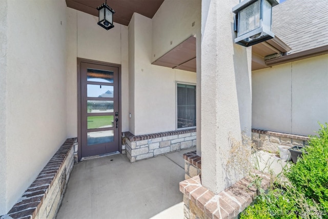 6107 E 127th St N, Collinsville, OK 74021 - doorway to property featuring stone siding, stucco siding, and roof with shingles