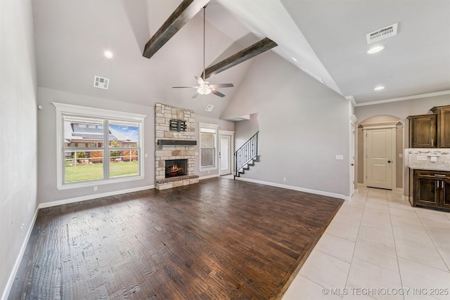 6107 E 127th St N, Collinsville, OK 74021 - unfurnished living room with a fireplace, a ceiling fan, high vaulted ceiling, stairs, and arched walkways