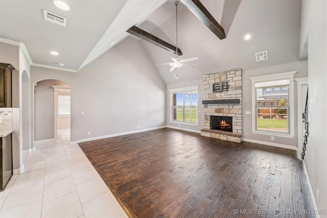 6107 E 127th St N, Collinsville, OK 74021 - unfurnished living room with a ceiling fan, arched walkways, a fireplace, beam ceiling, and high vaulted ceiling