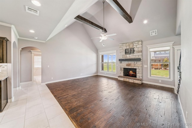 6107 E 127th St N, Collinsville, OK 74021 - unfurnished living room with ceiling fan, arched walkways, a stone fireplace, beamed ceiling, and high vaulted ceiling