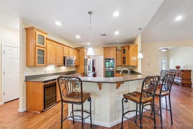 1701 N Skinner Ave, Drumright, OK 74030 - kitchen featuring appliances with stainless steel finishes, beverage cooler, a breakfast bar, a peninsula, and light wood-style floors
