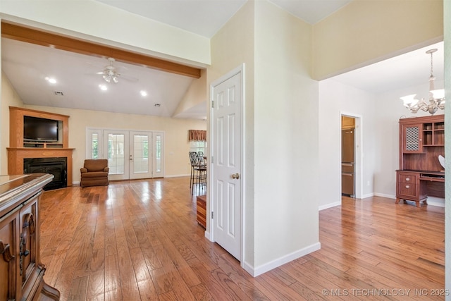 1701 N Skinner Ave, Drumright, OK 74030 - living area with light wood-style flooring, a glass covered fireplace, a ceiling fan, beam ceiling, and a chandelier