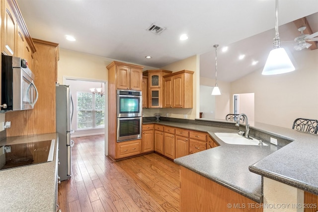 1701 N Skinner Ave, Drumright, OK 74030 - kitchen with stainless steel appliances, light wood-type flooring, hanging light fixtures, a peninsula, and glass insert cabinets