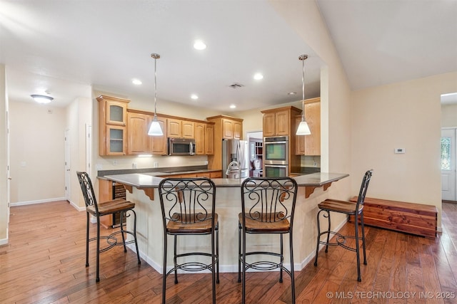 1701 N Skinner Ave, Drumright, OK 74030 - kitchen featuring appliances with stainless steel finishes, a peninsula, light wood-style floors, a kitchen bar, and recessed lighting