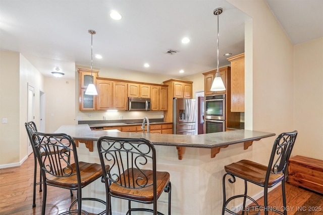 1701 N Skinner Ave, Drumright, OK 74030 - kitchen with stainless steel appliances, light wood-style floors, a peninsula, a kitchen breakfast bar, and recessed lighting