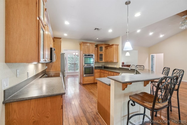 1701 N Skinner Ave, Drumright, OK 74030 - kitchen with appliances with stainless steel finishes, a breakfast bar area, a peninsula, light wood-style floors, and glass insert cabinets