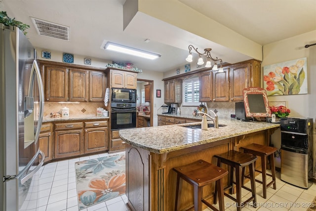 1605 N Skinner Ave, Drumright, OK 74030 - kitchen with black appliances, a peninsula, tasteful backsplash, light tile patterned flooring, and a kitchen breakfast bar