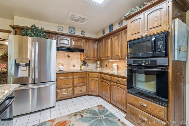 1605 N Skinner Ave, Drumright, OK 74030 - kitchen featuring black appliances, backsplash, light tile patterned floors, light stone counters, and brown cabinets