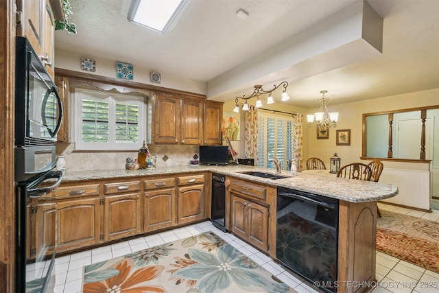 1605 N Skinner Ave, Drumright, OK 74030 - kitchen with black appliances, a peninsula, a chandelier, tasteful backsplash, and brown cabinets