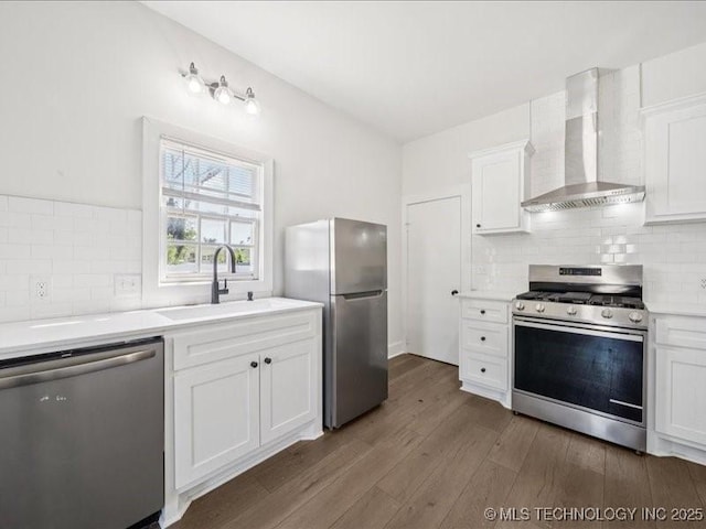 402 E Patti Page Blvd, Claremore, OK 74017 - kitchen featuring appliances with stainless steel finishes, wall chimney range hood, light countertops, wood finished floors, and white cabinets