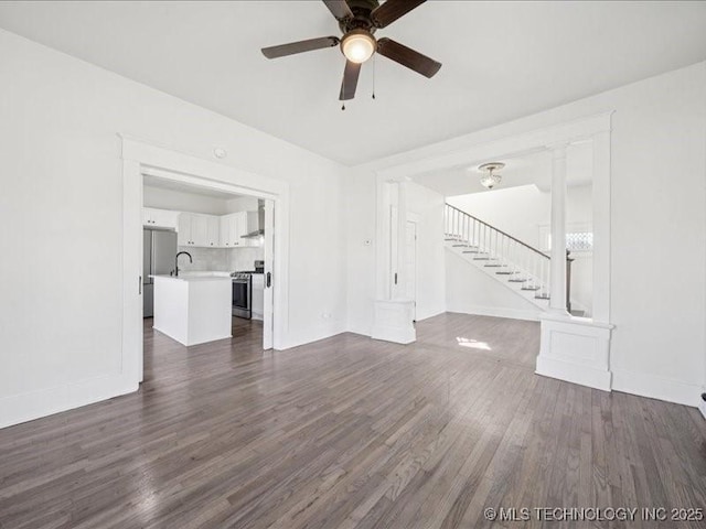 402 E Patti Page Blvd, Claremore, OK 74017 - unfurnished living room featuring a ceiling fan, stairway, and dark wood finished floors