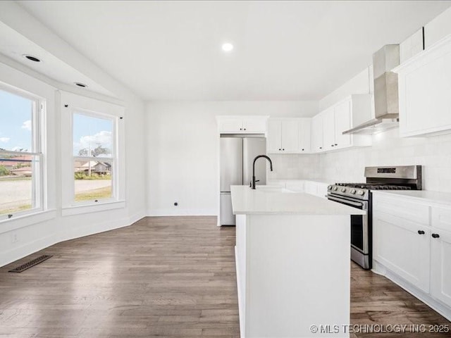 402 E Patti Page Blvd, Claremore, OK 74017 - kitchen with stainless steel appliances, an island with sink, wall chimney exhaust hood, light countertops, and wood finished floors