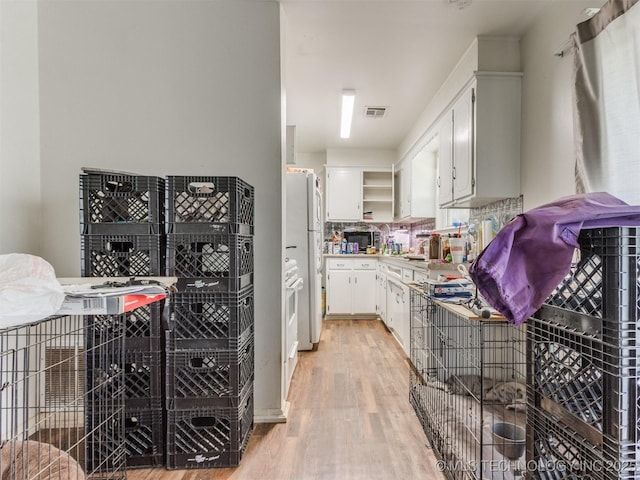 6330 Norman Ave, Oklahoma City, OK 73122 - kitchen with open shelves, light wood-style floors, freestanding refrigerator, backsplash, and white cabinets