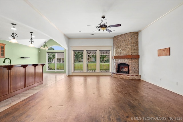 7816 E Galveston St, Broken Arrow, OK 74014 - unfurnished living room with ceiling fan, ornamental molding, light wood-style flooring, a large fireplace, and vaulted ceiling