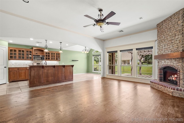7816 E Galveston St, Broken Arrow, OK 74014 - unfurnished living room featuring a fireplace, ceiling fan, light wood-style floors, recessed lighting, and a chandelier