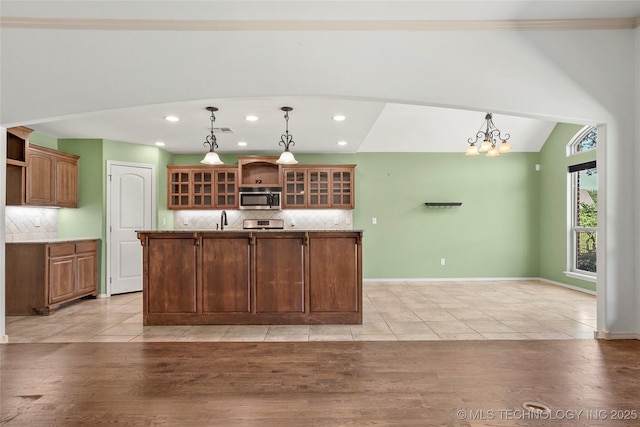 7816 E Galveston St, Broken Arrow, OK 74014 - kitchen with stainless steel microwave, open shelves, decorative backsplash, a kitchen island with sink, and hanging light fixtures