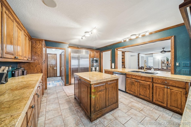 4704 W 88th St, Tulsa, OK 74132 - kitchen with built in appliances, a kitchen island, ceiling fan, brown cabinets, and ornamental molding