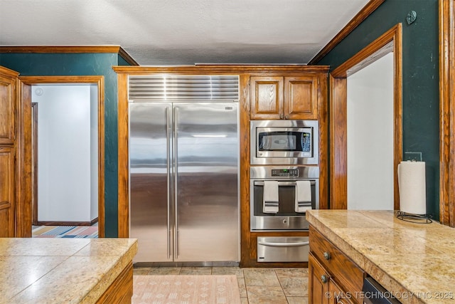 4704 W 88th St, Tulsa, OK 74132 - kitchen featuring built in appliances, a warming drawer, brown cabinets, and crown molding