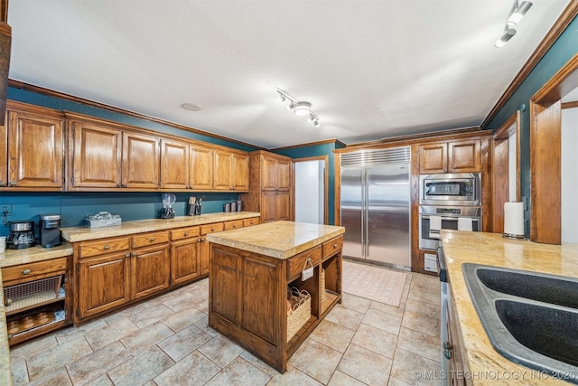 4704 W 88th St, Tulsa, OK 74132 - kitchen featuring built in appliances, open shelves, brown cabinetry, a kitchen island, and rail lighting