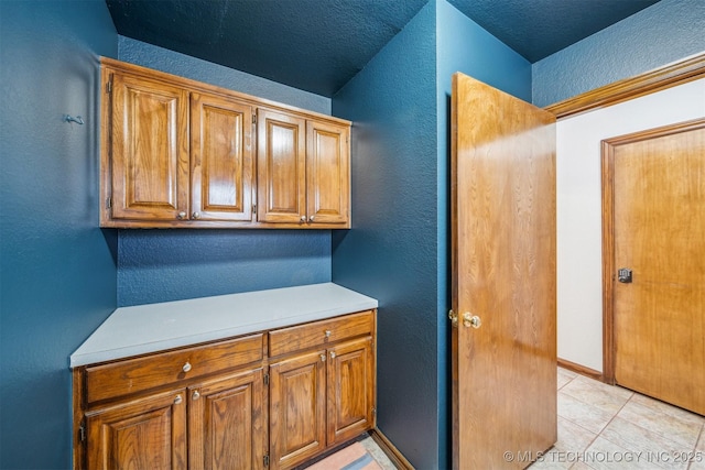 4704 W 88th St, Tulsa, OK 74132 - kitchen featuring a textured wall, light countertops, and brown cabinetry