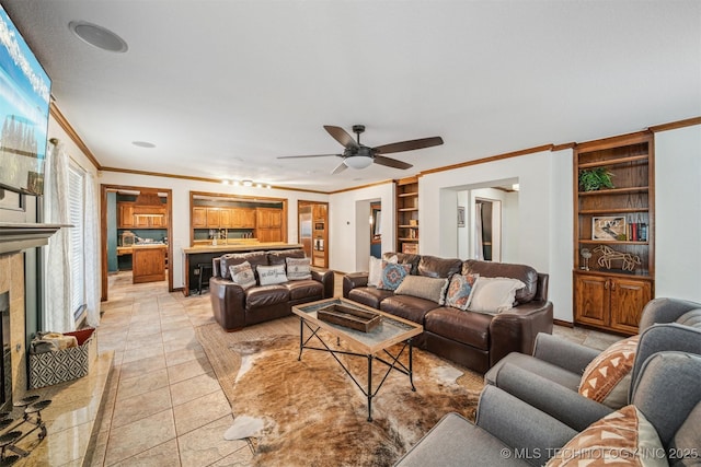 4704 W 88th St, Tulsa, OK 74132 - living area featuring crown molding, built in features, a ceiling fan, a tile fireplace, and light tile patterned floors