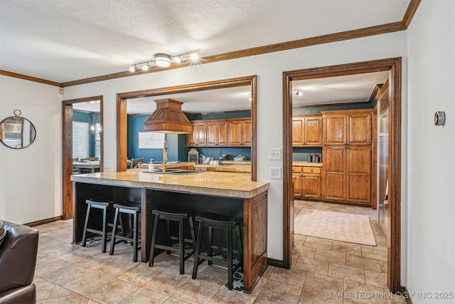 4704 W 88th St, Tulsa, OK 74132 - kitchen with light countertops, a kitchen bar, crown molding, brown cabinetry, and a textured ceiling