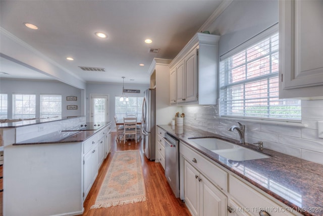 8414 E 99th Pl, Tulsa, OK 74133 - kitchen with stainless steel appliances, light wood finished floors, backsplash, recessed lighting, and dark stone counters