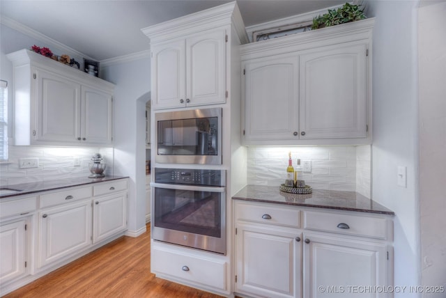 8414 E 99th Pl, Tulsa, OK 74133 - kitchen featuring appliances with stainless steel finishes, dark stone counters, white cabinetry, decorative backsplash, and ornamental molding