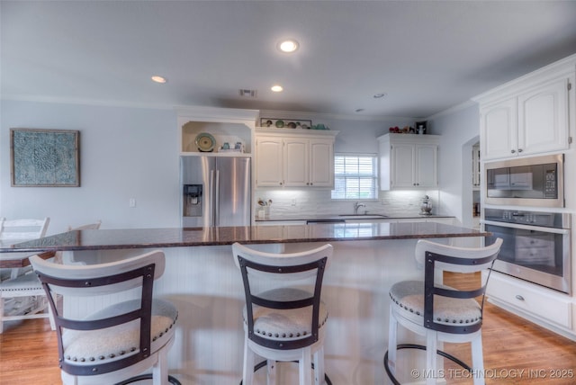 8414 E 99th Pl, Tulsa, OK 74133 - kitchen with appliances with stainless steel finishes, white cabinets, open shelves, a breakfast bar, and recessed lighting