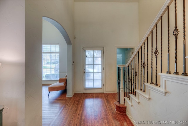 8414 E 99th Pl, Tulsa, OK 74133 - entrance foyer featuring arched walkways, wood finished floors, a high ceiling, and stairs