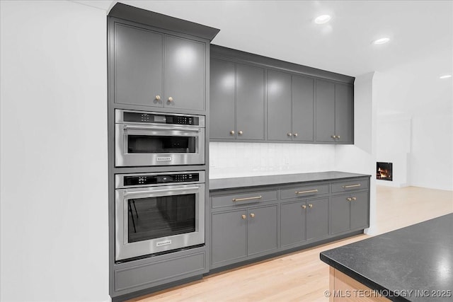 4155 S Birmingham Pl, Tulsa, OK 74105 - kitchen with double oven, dark countertops, light wood-type flooring, recessed lighting, and gray cabinets