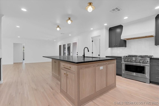 4155 S Birmingham Pl, Tulsa, OK 74105 - kitchen featuring stainless steel range, light brown cabinetry, decorative backsplash, light wood-type flooring, and an island with sink