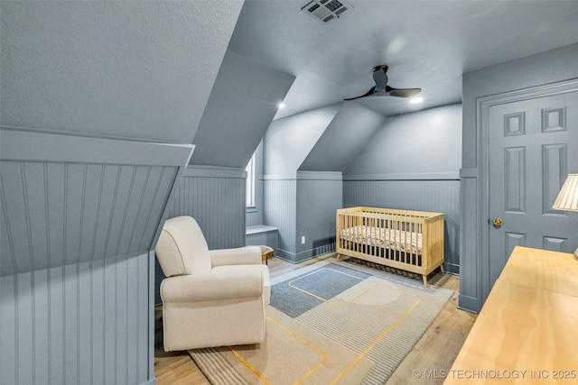 5414 E 109th Pl, Tulsa, OK 74137 - bedroom with wood finished floors, a nursery area, lofted ceiling, and a wainscoted wall