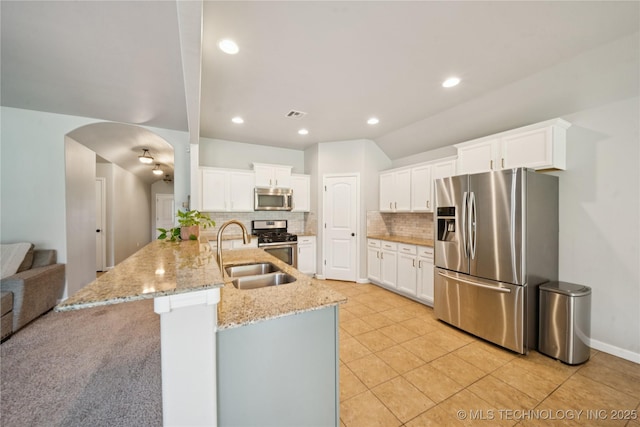 9246 N 143rd E Ave, Owasso, OK 74055 - kitchen featuring stainless steel appliances, a peninsula, backsplash, arched walkways, and light stone counters