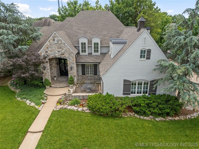 4620 E 108th Pl S, Tulsa, OK 74137 - french country home with stone siding, a front yard, stucco siding, roof with shingles, and a patio area